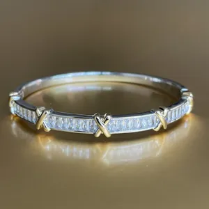 Macro detail of two-tone gold and silver bracelet with baguette-cut crystals and X-accents
