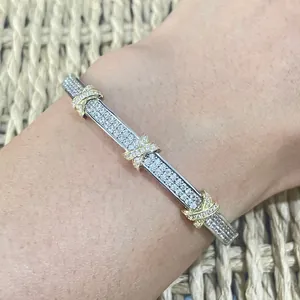 Close-up of gold X-shaped cross charms on a luxury crystal-encrusted bangle bracelet