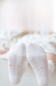 Close-up of white mesh girls socks featuring delicate floral embroidery and lace cuffs