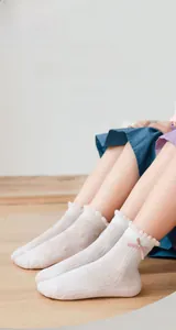 Close-up of white breathable mesh socks with pink floral embroidery and bows for girls