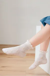 Close-up of white mesh girls socks with pink floral patterns and ruffle cuffs