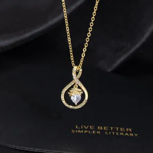 Close-up of golden graduation necklace with heart zircon and engraved quote