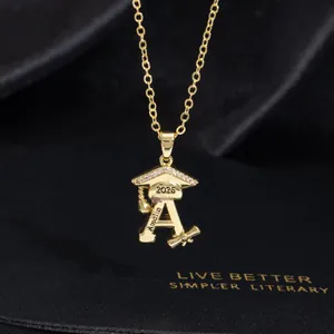 Detail of 2026 graduation necklace with crystal cap, custom name A, and gold scroll charm