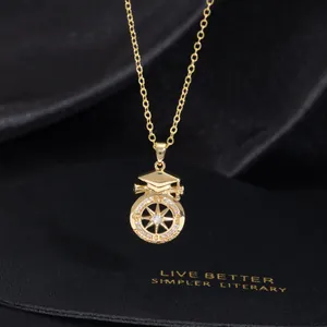 Detail of a gold graduation cap pendant with a starburst compass and zircon inlay