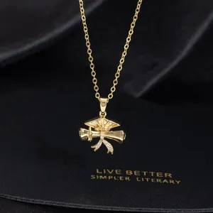 Macro view of gold graduation cap and scroll pendant with rhinestones on a black background