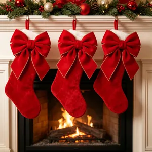 Three red velvet Christmas stockings with large gold-edged bows hanging on a fireplace