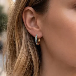 Close-up of 18K gold hoop earrings with three rows of shimmering light blue zircon stones