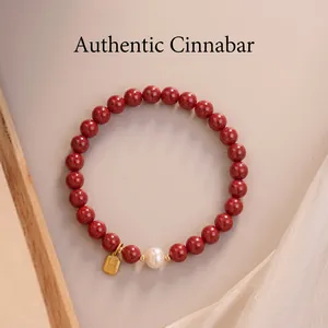 Detailed view of cinnabar bead bracelet with white pearl and golden textured charm