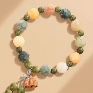 Detailed close-up of beaded bracelet with lotus pendant and floral carved beads