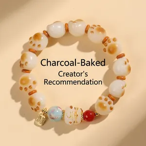 Detailed view of beaded bracelet with cat paw charms and a golden Fu character pendant