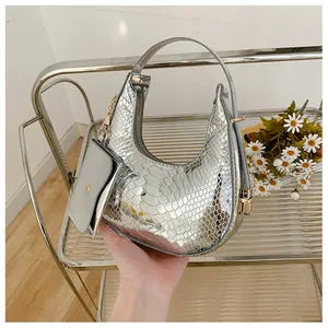 Close-up of silver crescent handbag with faux snakeskin texture and golden chain hardware