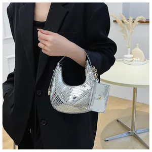 Chic silver snakeskin crossbody bag with mini charm pouch shown on a black suit blazer