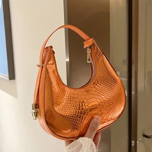 Metallic orange crescent handbag with snake skin texture and gold hardware details
