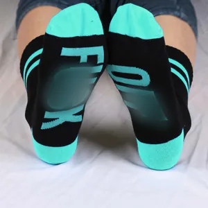 Funny black and teal crew socks featuring bold knit lettering on the soles