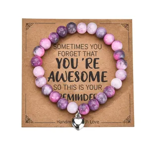 Detail of pink zebra stone bead bracelet with a silver heart charm on a gift display card