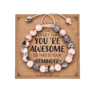 Macro view of handmade stone bead heart bracelet with adjustable cord on kraft paper card