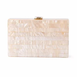 Detail of elegant ivory pearlescent acrylic evening clutch with gold metal clasp