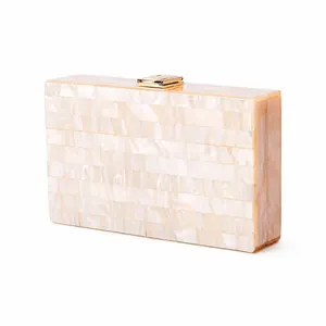 Detailed close-up of cream pearlescent acrylic evening clutch with gold metal clasp