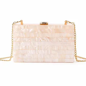 Detail of cream acrylic clutch bag featuring striped marble texture and gold metal clasp