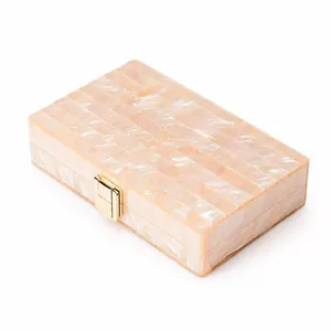 Detailed side view of pearlescent acrylic evening clutch with gold metal clasp