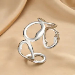 Close-up of polished silver geometric open bangle on elegant champagne satin fabric