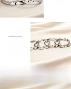 Detailed view of minimalist silver rings with engraved letters on smooth metal band