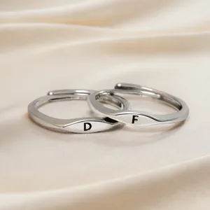 Minimalist silver initial rings with engraved letters D and F on champagne silk fabric