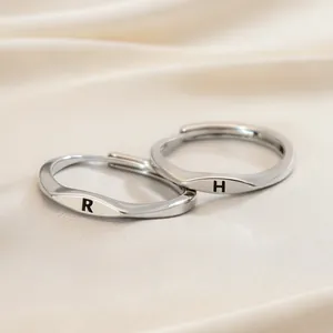 Two minimalist silver-tone adjustable open rings with engraved letters R and H detail