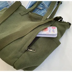 Detail of army green corduroy tote bag showing metal zipper pocket and texture