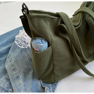 Close-up of green corduroy tote bag side pocket with umbrella showing texture and storage