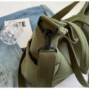 Detail of green corduroy tote bag featuring black matte metal D-ring and strap hardware