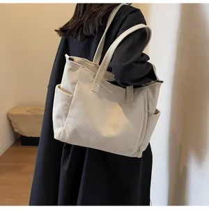 Detail of off-white corduroy tote bag showing ribbed texture and side pocket on a model