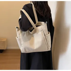 Detail view of large corduroy tote bag featuring side pockets and textured ribbed fabric