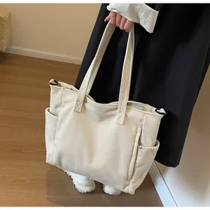 Detail view of corduroy tote bag featuring reinforced handles and side pocket design
