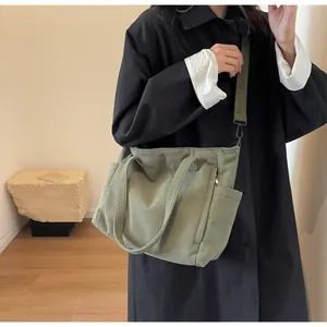 Detail view of corduroy tote bag side pockets and adjustable shoulder strap in green