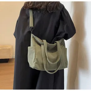 Model view of olive corduroy tote bag showing large side pocket and fabric shoulder strap