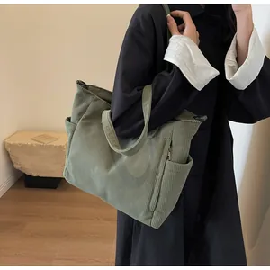 Detail view of grass green corduroy tote bag featuring side pockets and a hidden front zip
