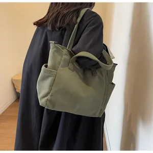 Close-up of olive green corduroy tote bag showing side pocket detail for water bottles