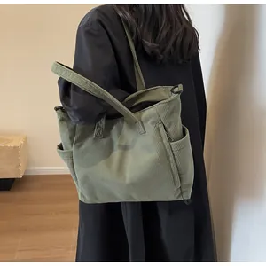 Detail of the gray-green corduroy tote bag showing side pockets and soft ribbed texture