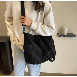 Detail of black corduroy tote bag showing spacious side pocket and woven shoulder strap