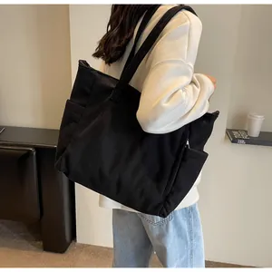 Detailed side view of black corduroy tote bag showing textured stripes and side pocket