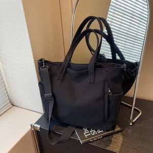 Large black corduroy tote bag with adjustable shoulder strap and multiple pockets