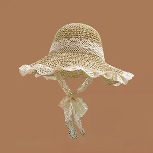 Close-up of beige straw hat featuring elegant white lace trim and scalloped brim details