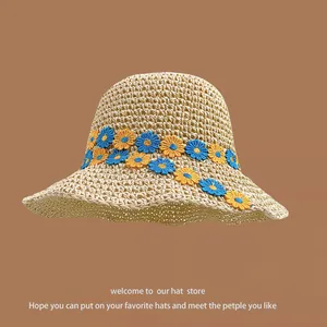 Close-up of straw sun hat featuring intricate blue and orange sunflower embroidery detail