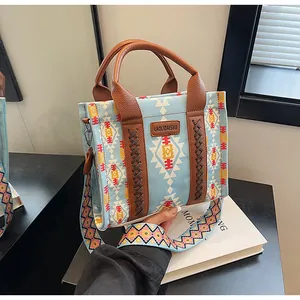 Detail of bohemian canvas tote with geometric prints and brown leather handles on books
