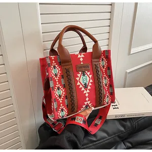 Close-up of red canvas tote with ethnic patterns, leather handles and wide shoulder strap