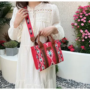 Close-up of red ethnic canvas bag with geometric patterns and brown leather handle