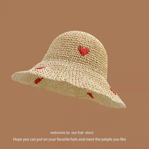 Beige woven straw sun hat featuring red heart embroidery for a sweet summer look