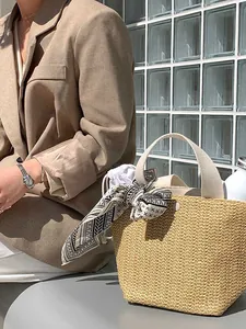 Detail of woven straw bucket bag featuring canvas handles and geometric print silk scarf