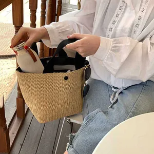 Detail of woven straw tote bag with black handles showing spacious capacity and metal clasp